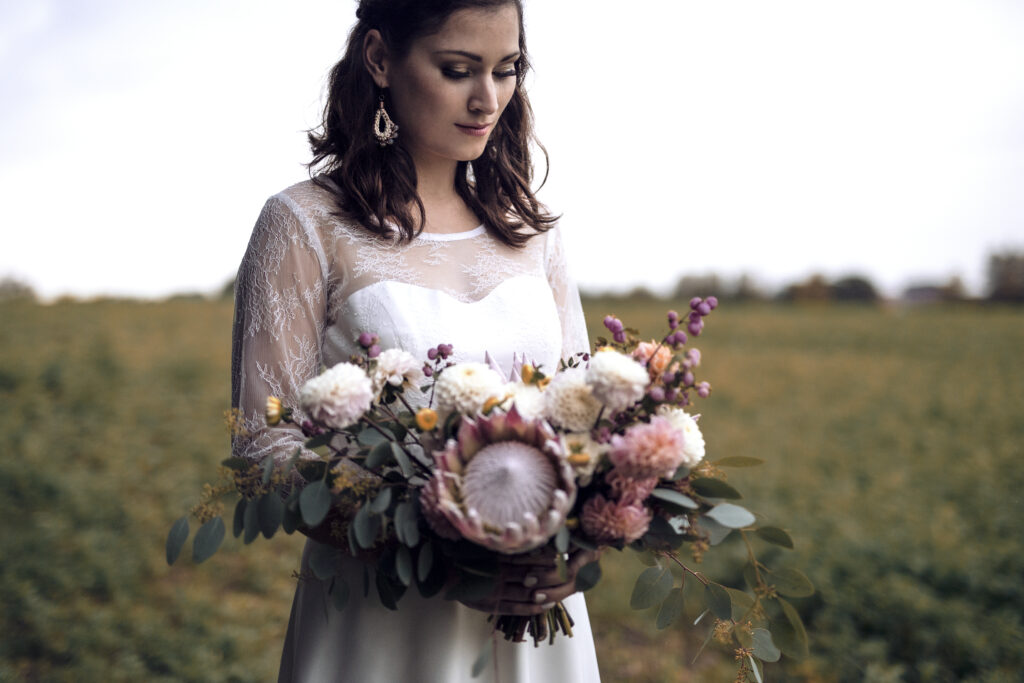 Brautstrauß mit Dahlien und Protea sowie Eukalyptus, kurzes Brautkleid mit Spitze